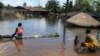 People sit in front of a submerged building in the Patani community in Nigeria's Delta state, which was recently hit by severe floods, October 15, 2012.