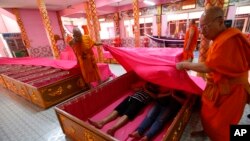 Los participantes sostuvieron flores e incienso mientras los monjes los cubrían con sábanas rosas y cantaron oraciones para los muertos.
