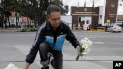 Un hombre coloca flores en un memorial improvisado frente a la Academia de Policía General Francisco de Paula Santander, un día después de que explotara un coche bomba en el lugar.