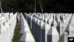 A Bosnian Muslim woman reacts as she walks among gravestones at the memorial centre of Potocari near Srebrenica, 150 kms north east of Sarajevo, Bosnia, Aug. 14, 2018.