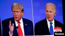 El presidente estadounidense Joe Biden (der) y el ex presidente y candidato presidencial republicano Donald Trump son vistos en un proyector de pantalla durante una celebración de la Coalición Conservadora de Michigan en Novi, Michigan, EEUU, el 27 de junio de 2024.