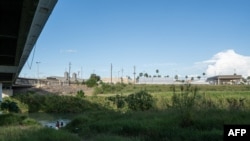 Migrantes lavan ropa y se bañan en las orillas mexicanas del Río Grande. Por encima está el Puente Internacional en Matamoros, estado de Tamaulipas, México, el 5 de noviembre de 2019.