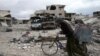 FILE - A man walks with his bicycle at a damaged site in the besieged town of Douma, Eastern Ghouta, near Damascus, Syria, March 30, 2018.