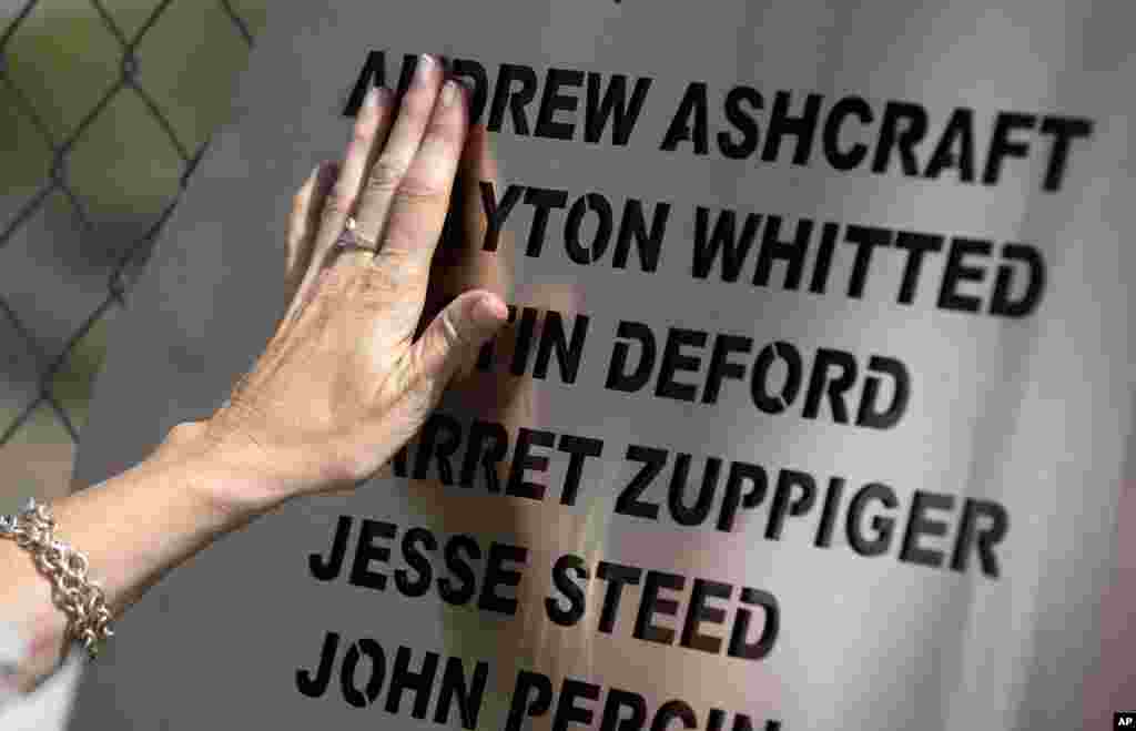 Linda Lambert places her hand across a plaque hanging on the fence outside the Granite Mountain Interagency Hotshot Crew fire station in Prescott, Arizona, July 2, 2013. 