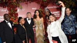 ARCHIVO - George y Amal Clooney, en el centro, posan para una fotografía con parte de los homenajeados en los Premios Albie que entrega su Fundación, en la Biblioteca Pública de Nueva York, el 29 de septiembre de 2022.