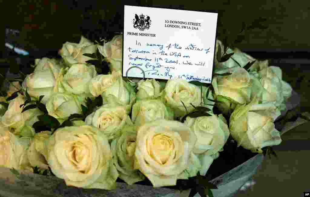 Kartu bertuliskan tangan Perdana Menteri Inggris Theresa May di atas karangan bunga mawar untuk menghormati para warga Inggris yang menjadi korban serangan 9/11 di taman Grosvenor Square dekat Kedutaan Besar AS di London (11/9).&nbsp;(AP/Alastair Grant)