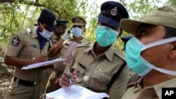 Indian police officers cover their faces with masks as they note details of charred bodies of passengers near the site of a train accident at Kothacheruvu, about 155 kilometers (96 miles) north of Bangalore, India, Saturday, Dec. 28, 2013.
