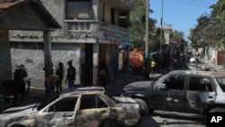Los residentes pasan junto a vehículos incendiados por bandas armadas en el barrio de Poste Marchand de Puerto Príncipe, Haití, el martes 10 de diciembre de 2024. 