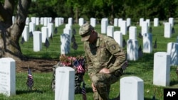 Un soldado coloca una badera frente a la tumba de un soldado caído en acción y sepultado en el Cementerio Nacioal de Arlington, Virginia.