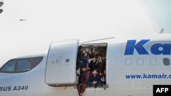 Los afganos se suben a un avión y se sientan junto a la puerta mientras esperan en el aeropuerto de Kabul en Kabul el 16 de agosto de 2021.