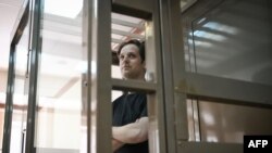 因间谍罪名在俄罗斯被捕的美国记者埃文·格什科维奇 (Evan Gershkovich)2023年6月22日站在莫斯科市法院像笼子一样的被告席，准备就他的长期拘留提出上诉。（法新社摄影）