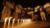 A boy places a candle as demonstrators hold placards during a candlelight march for a gang rape victim, who was assaulted in New Delhi, January 16, 2013. 