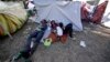 A Venezuelan refugee family rests outside a makeshift camp before going out to find any kind of work in Quito, Ecuador, Aug. 9, 2018.
