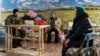 FILE - A Ukrainian soldier, left, guards as two elderly women wait to get a humanitarian aid in Avdiivka, eastern Ukraine, Feb. 5, 2017. 