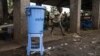 FILE - A boy runs past a dispenser containing water mixed with disinfectant, east of Mbandaka, DRC, May 23, 2018.