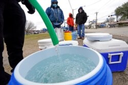 Se llena un barril de agua mientras otros esperan en temperaturas bajo cero para usar una manguera en el grifo de un parque en Houston, 18 de febrero de 2021. La electricidad volvió a Texas, pero muchos carecen de agua corriente.