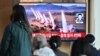 People watch a television screen showing a news broadcast with file footage of a North Korean missile test, at a railway station in Seoul on April 22, 2024.