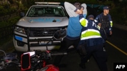 Foto divulgada por la Oficina de Prensa de la Presidencia de El Salvador muestra a un agente de la policía revisando a un hombre durante una acción contra pandilleros en San Marcos, El Salvador, el 28 de octubre de 2024.