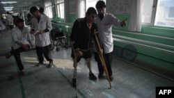 An Afghan doctor (R) assisting a survivor of a landmine blast at a hospital run by the International Committee of the Red Cross (ICRC) for war victims and the disabled in Kabul, Feb. 13, 2018.