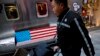 A delivery worker pushes a cart loaded with goods past by a bench with an American flag outside a fashion boutique selling U.S. brand clothing at the capital city's popular shopping mall in Beijing, Feb. 1, 2019. 