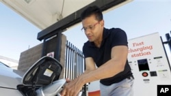 Seorang pengemudi sedang mengisi daya mobil listriknya di stasiun pengisi daya Sacramento Municipal Utility District, Sacramento, California, 17 September 2015. (Foto: Rich Pedroncelli/AP Photo)