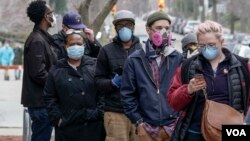 Electores con máscaras faciales hacen fila en la secundaria Riverside de Milwaukee, para votar en la elección primaria de Wisconsin, el 7 de abril de 2020.