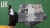 A man walks past a promotional banner showing a photograph of a pile of Nigerian naira along a road in Lagos November 24, 2010.