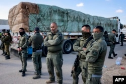 Soldados israelíes se encuentran junto a uno de los camiones egipcios que transportan suministros de ayuda humanitaria a la Franja de Gaza, en el lado israelí del cruce fronterizo de Kerem Shalom con el territorio palestino el 6 de febrero de 2024.
