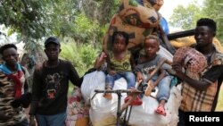 Congolese migrants expelled from Angola push a rented bicycle to transport their children and belongings along the road to Tshikapa, Kasai province near the border with Angola, in the Democratic Republic of the Congo, Oct. 12, 2018.