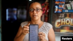 Roxana Valles muestra su teléfono mientras usa la aplicación Bitcoin Beach en su tienda en El Zonte Beach, Chiltiupán, El Salvador, el 10 de junio de 2021. 