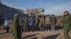 FILE - Ukrainian prisoners of war stand as Russia-backed separatists watch in front of the destoryed airport building outside Donetsk, Ukraine, Feb. 25, 2015.