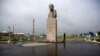 FILE - A woman walks past a statue of Soviet state founder Vladimir Lenin in Yuzhno-Kurilsk, the main settlement on the Southern Kuril island of Kunashir, Sept. 17, 2015. 