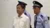 In this image taken from video, disgraced politician Bo Xilai, center, enters the courtroom, flanked by police guards at Jinan Intermediate People's Court in eastern China's Shandong province, Aug. 22, 2013. 
