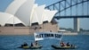 FILE - Members of the environmental group Greenpeace hold up a sign that reads "#LET THEM STAY" in front of the Opera House in Sydney, Australia, Feb. 14, 2016. 