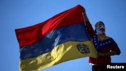 Un manifestante enmascarado ondea una bandera de Venezuela durante una protesta en favor del opositor Juan Guaidó, en Buenos Aires, el 2 de febrero de 2019.