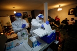El enfermero Alejandro Ramírez, en el centro, prepara material para el Dr. Iván Mandujano mientras realizan pruebas de COVID-19 en una casa en el distrito Xochimilco de la Ciudad de México, el jueves 24 de septiembre de 2020.