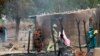 People stand near burnt structures in the aftermath of what Nigerian authorities said was heavy fighting between security forces and Islamist militants in Baga, a fishing town on the shores of Lake Chad, adjacent to the Chadian border, April 21, 2013. 