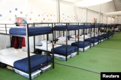 Literas en una tienda de campaña en Tornillo, Texas, que alberga a niños migrantes separados de sus padres o que han cruzado la frontera de EE.UU. sin acompañante. Foto del Departamento de Salud y Servicios Humanos de EE.UU.