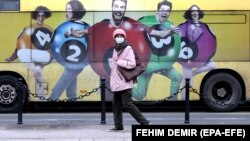 A woman wearing a face mask walks in Sarajevo. EPA-EFE/FEHIM DEMIR