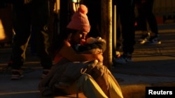 Una mujer lleva a un bebé mientras los migrantes, que tenían una cita con la aplicación CBP One de la aduana de EEUU, se reúnen para obtener información cerca del puente fronterizo internacional Paso del Norte en Ciudad Juárez, México, el 21 de enero de 2025. 