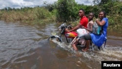 A man rides a motorcycle with passengers along a flooded road in the Patani community in Nigeria's Delta state, October 15, 2012. 