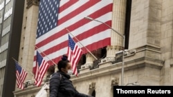 Un peatón con mascarilla pasa delante de la Bolsa de Valores Nueva York, cuando los mercados siguen reaccionando a la crisis económica generada por la pandemia de COVID-19.