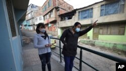 Los migrantes venezolanos Yaquelin Timaure, a la derecha, y su hija Andreina Timaure, parados en una acera en su vecindario en Bogotá, Colombia, el lunes 21 de diciembre de 2020. [AP]