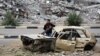 A Palestinian child stands inside a damaged car in front of a destroyed building in the war-devastated Bureij refugee camp in the central Gaza Strip on Feb. 7, 2025. 