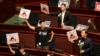 在香港特首林郑月娥回答立法会议员有关其政策报告的问题时，民主派议员举起“五大诉求，缺一不可”的标语牌。（2019年10月17日）