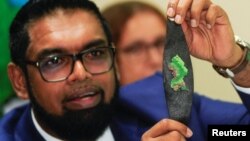 El presidente guyanés Irfaan Ali muestra a la prensa un brazalete con la imagen impresa del Esequibo, luego de reunirse el jueves con su homólogo venezolano Nicolás Maduro en San Vicente y las Granadinas.