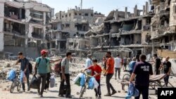 La gente camina entre escombros y edificios dañados en el distrito de Tuffah, al este de la ciudad de Gaza, el 8 de julio de 2024, en medio del conflicto en curso en el territorio palestino entre Israel y Hamás.