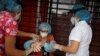 Arcelia Aguilar, residente del hogar de ancianos "Los Abuelitos" es ayudada por dos enfermeras a colocarse equipos de protección para poder recibir un abrazo de su sobrina a través de una pared plástica en El Salvador, el 1 de septiembre de 2020.