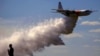 A television reporter stands in front of a Large Air Tanker (LAT) C-130 Hercules, also known as ‘Thor,’ as it drops a load of around 15,000 liters of retardant during a display ahead of the bushfire season, at RAAF Base Richmond, Sydney, Australia, Sept. 1, 2017.