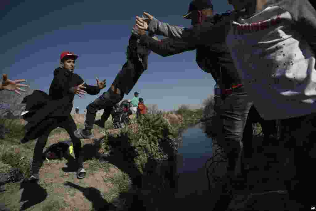 Los inmigrantes pasan a un niño a las alturas del Ro Grande en Ciudad Járez, México el 29 de marzo de 2023. Las imágenes retratan las vicisitudes de los inmigrantes por alcanzar el territorio de EEUU. [Foto:&nbsp;Christian Chavez}